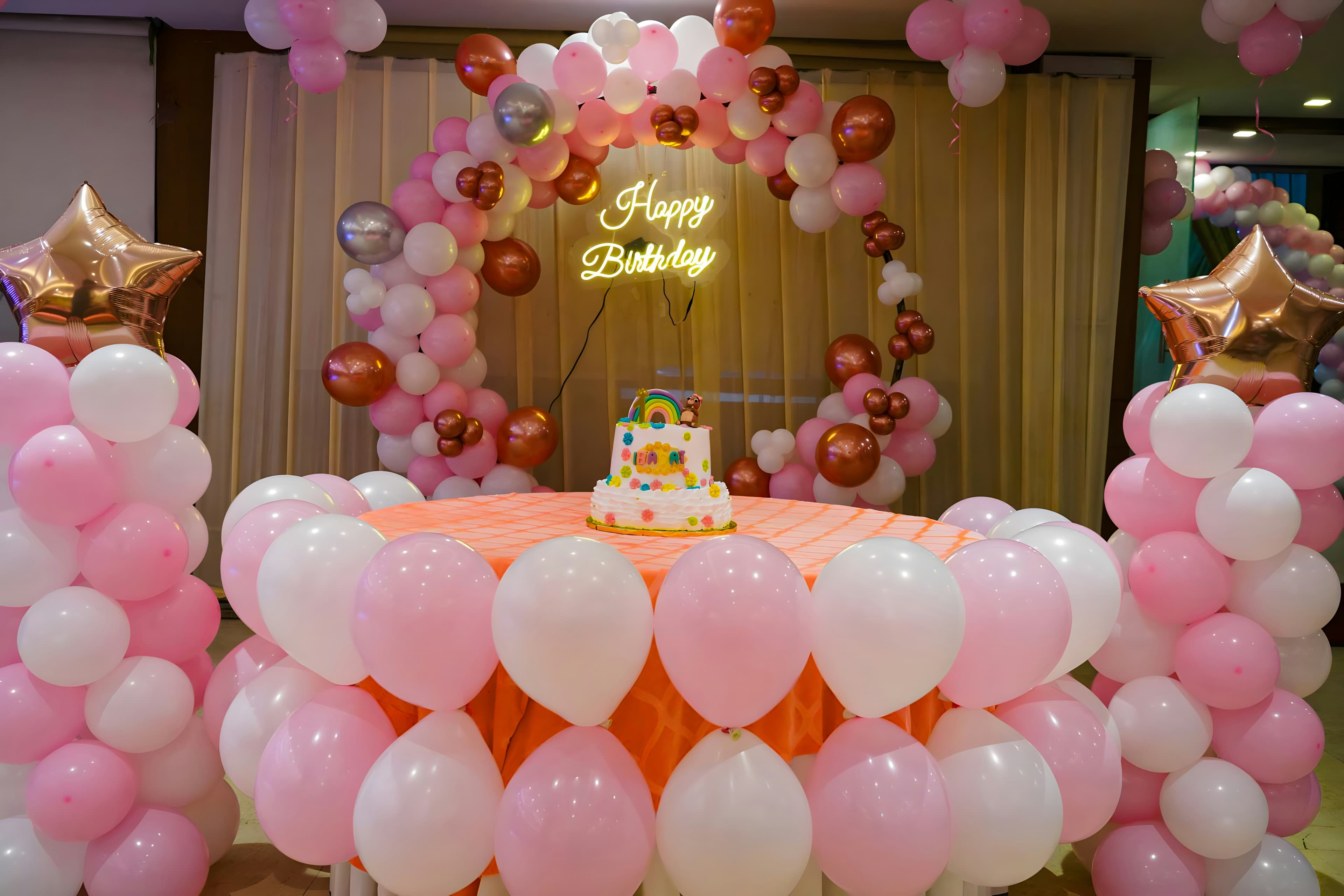 Birthday cake framed by an arch of pink, white and metallic balloons