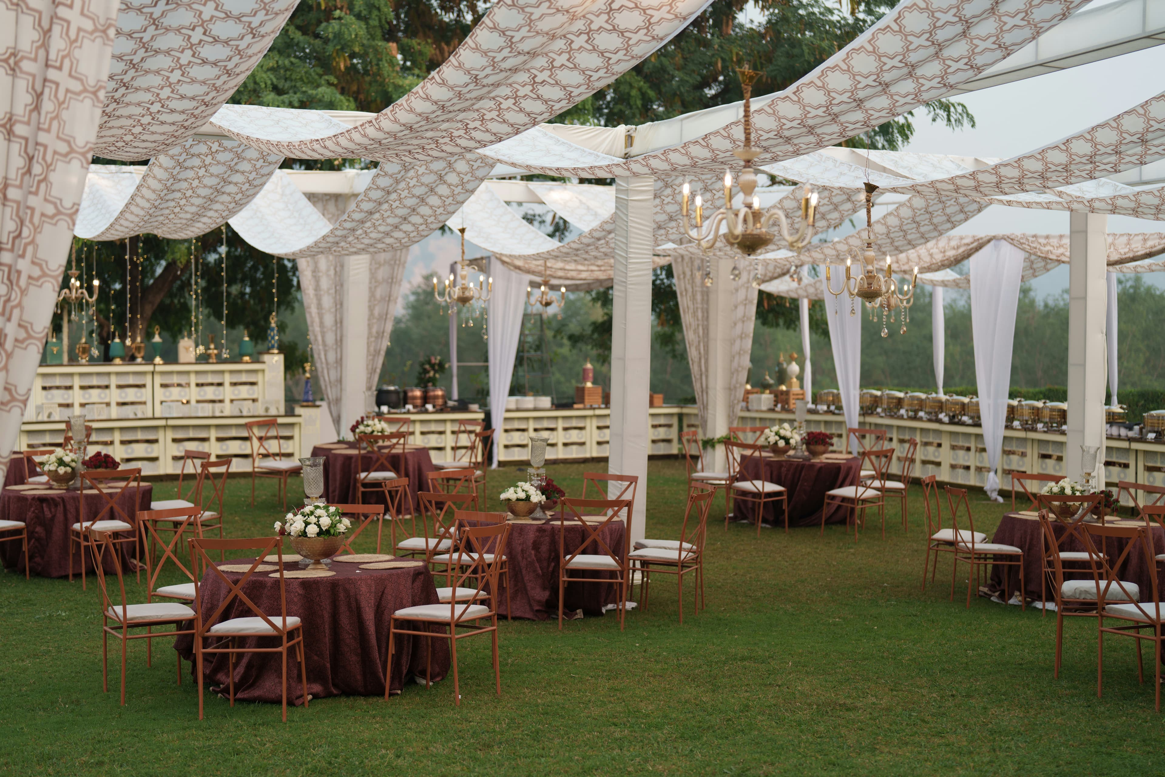 Garden reception with draped fabric, chandeliers and decorated tables